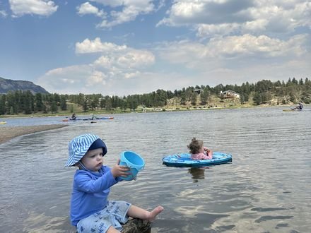 Two kids playing at the edge of a mountain lake
