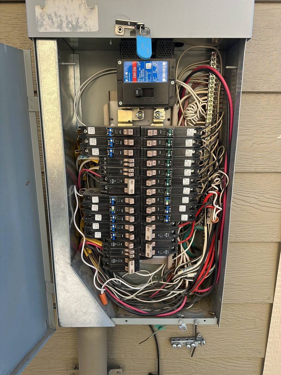 Outdoor electrical panel with the cover off, showing two rows of breakers and the wiring behind them