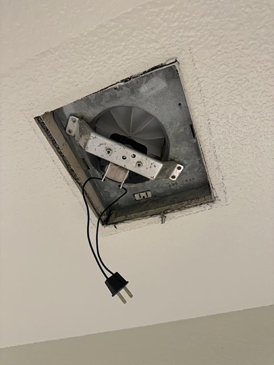Old bathroom exhaust fan removed from the ceiling during replacement