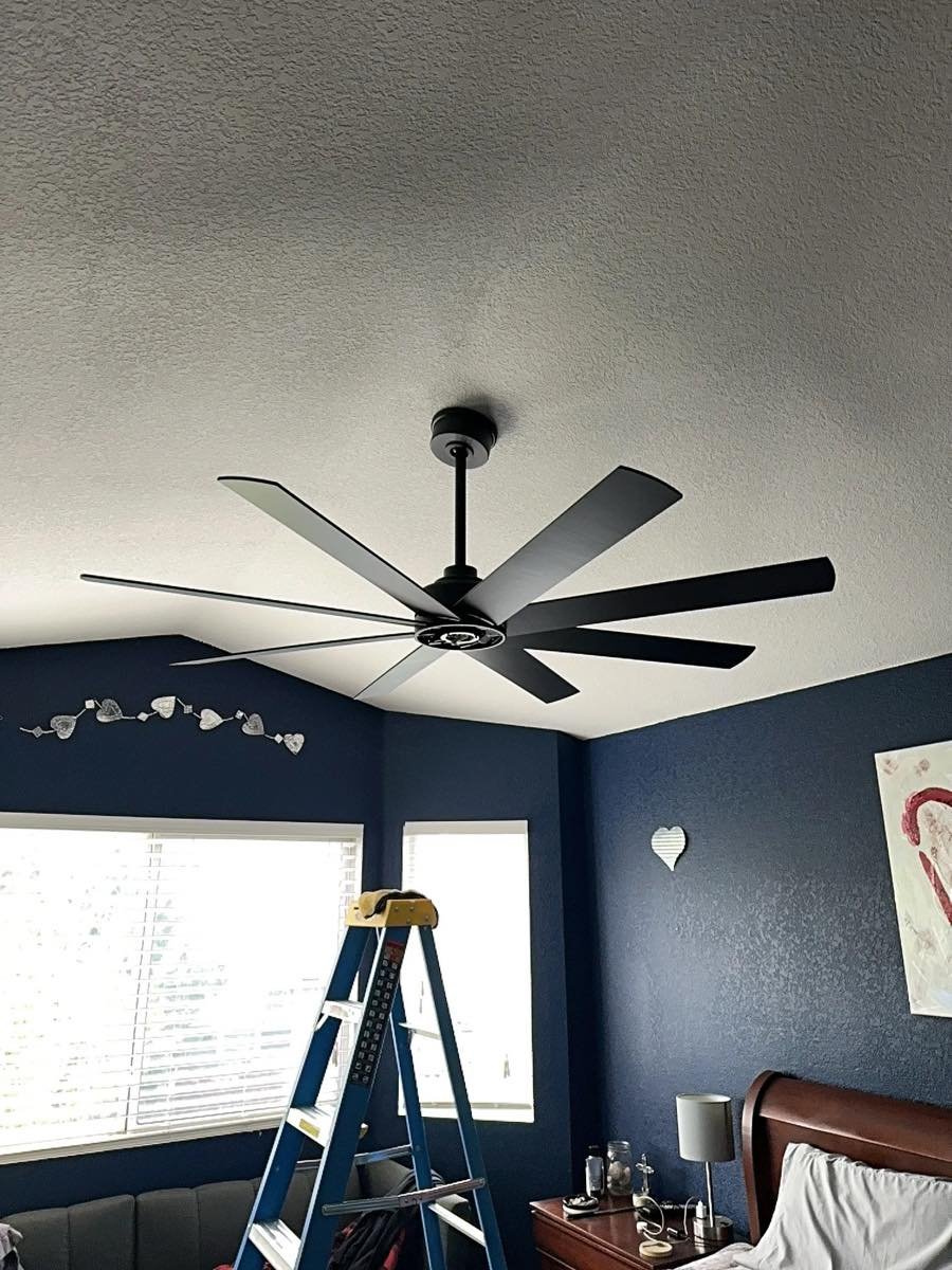 Large black eight-blade ceiling fan installed on a bedroom ceiling