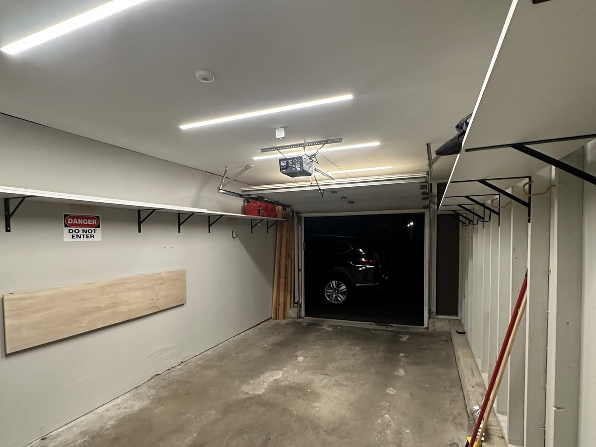 Garage with recessed ceiling lights on and the door open to a car