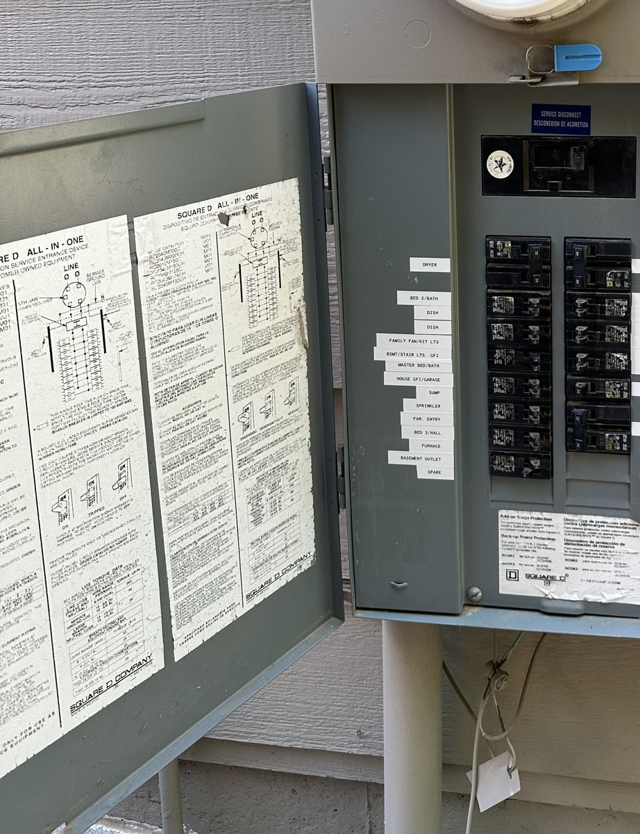 Open outdoor panel with a printed label beside every breaker naming the room it feeds