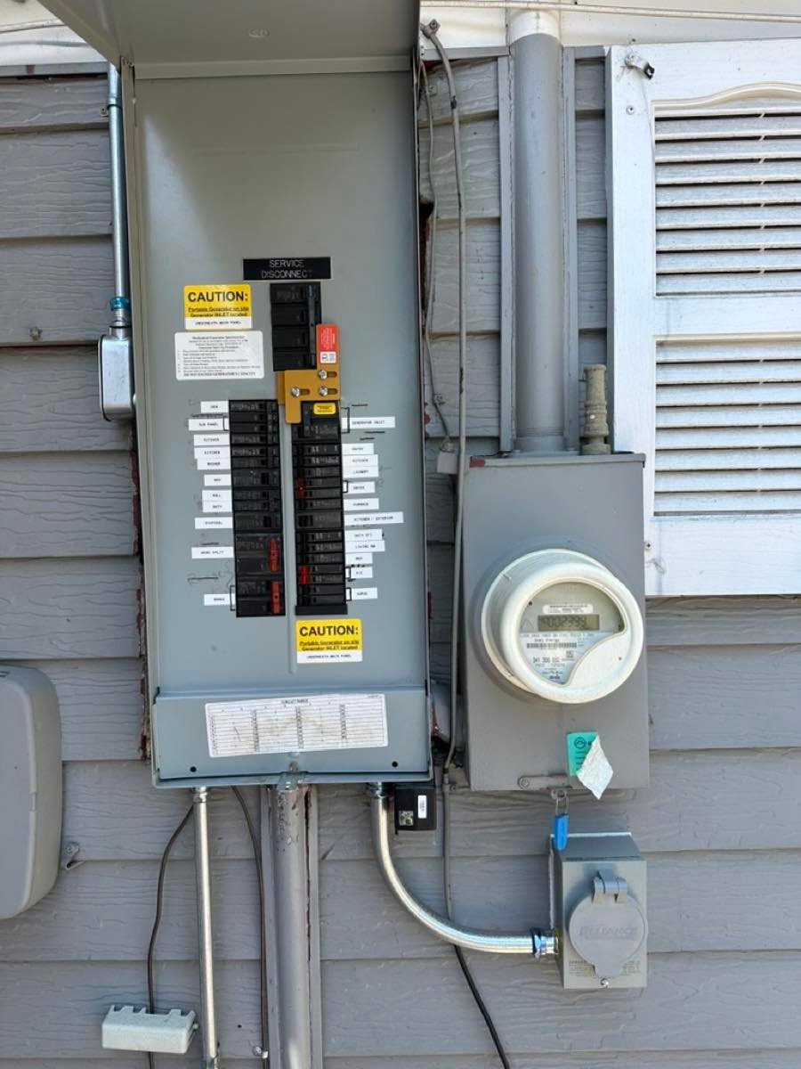 Outdoor electrical panel with a generator interlock, every breaker labeled, and caution labels beside the meter