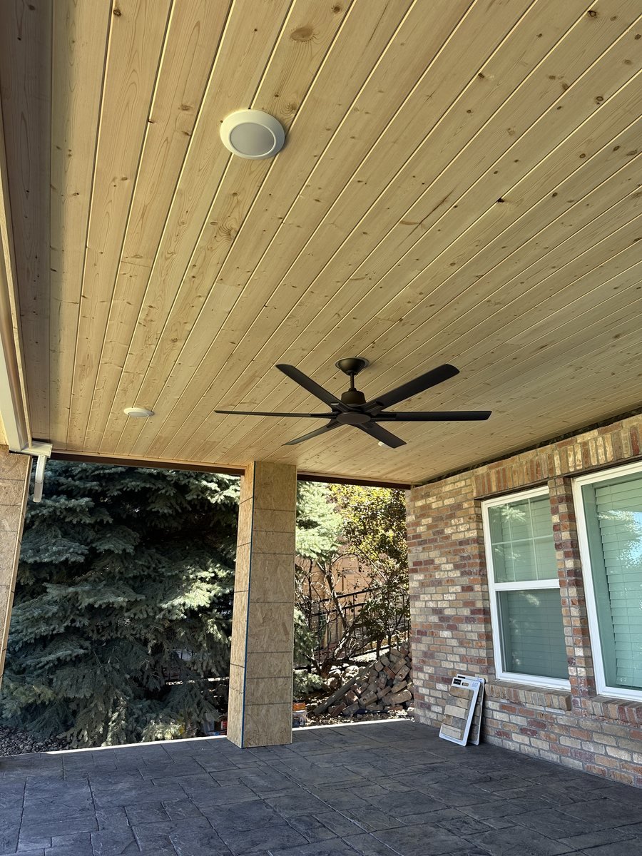 Large black ceiling fan and recessed can lights in a tongue-and-groove patio ceiling