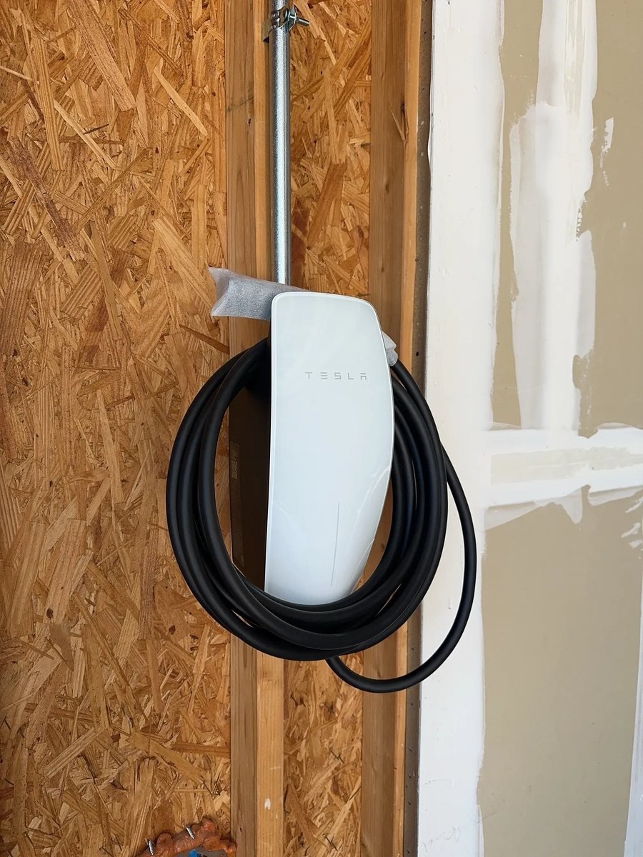 Tesla Wall Connector mounted to a garage wall stud with conduit running up the framing